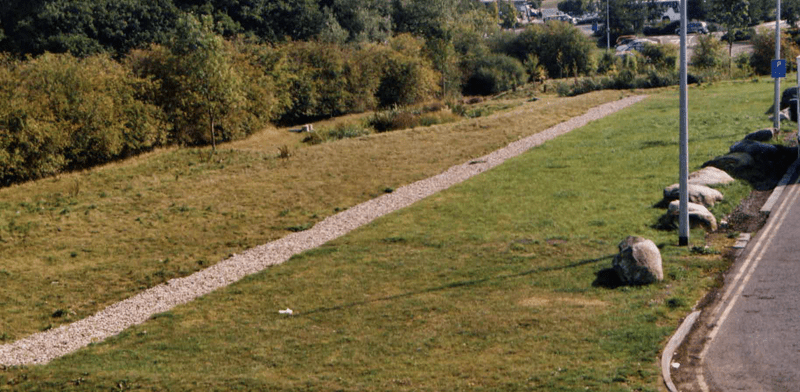 Filter drain beside a wide filter strip receiving runoff from a HGV parking area at Hopwood Motorway Services.